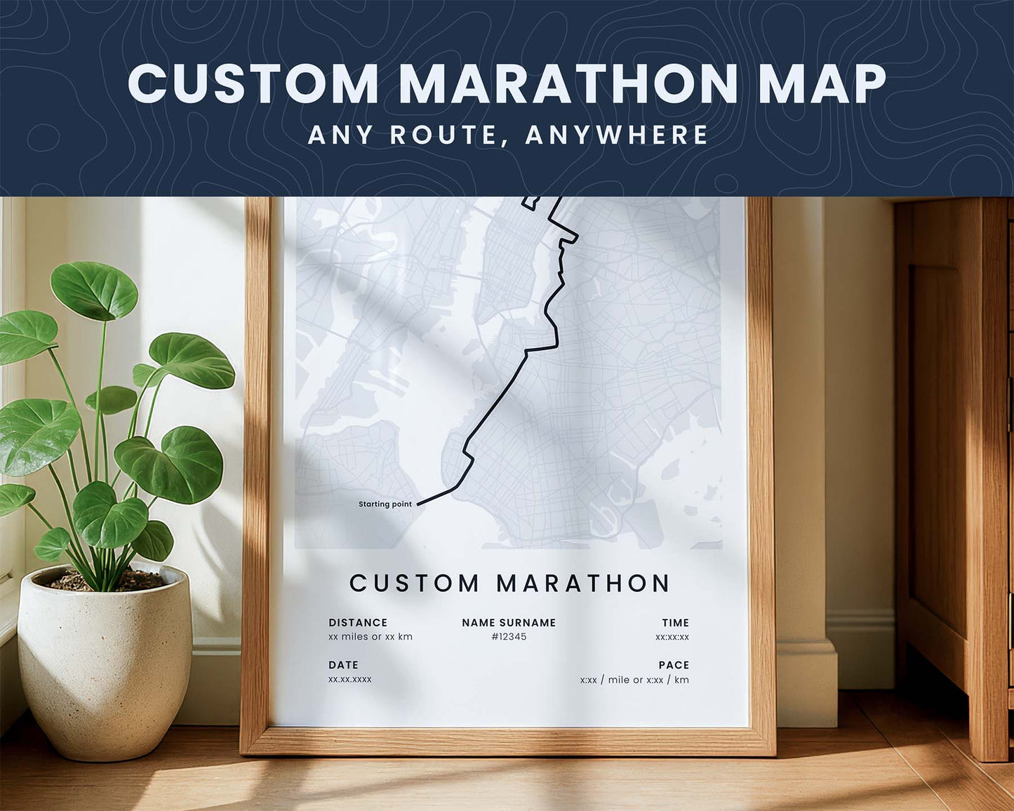 Framed custom marathon map on a wall with a plant and wooden cabinet in the background.